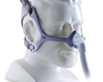 A mannequin head wearing a CPAP nasal mask with straps and a connected hose.