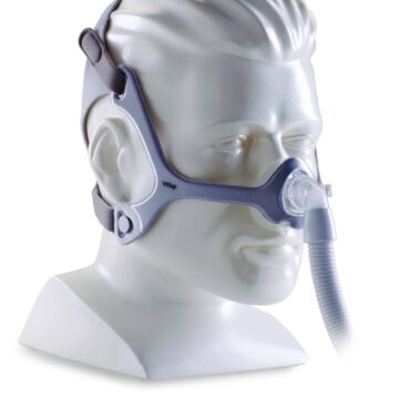 A mannequin head wearing a CPAP nasal mask with straps and a connected hose.