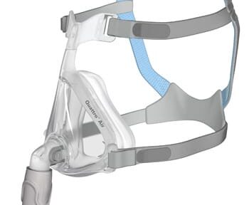 Clear CPAP face mask with gray and blue straps and a hose connector, shown from a side angle.