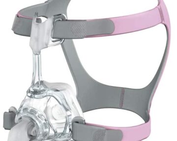 A pink and gray CPAP mask and headgear, designed for sleep apnea therapy, shown on a white background.