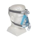 A mannequin head wearing a full-face CPAP mask with head straps and a blue cushion.