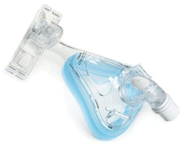 Clear full-face CPAP mask with blue silicone lining and plastic headgear attachment, viewed from above.