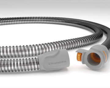 A close-up of a flexible gray medical hose with an orange connector on one end.