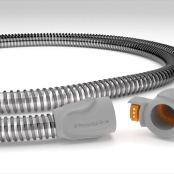 A close-up of a flexible gray medical hose with an orange connector on one end.