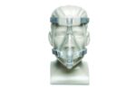 A medical mannequin head wearing a clear CPAP face mask with gray straps.