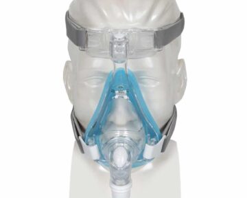 Clear mannequin head wearing a full-face CPAP mask with blue and gray straps, shown from the front.