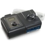 A black CPAP machine with a digital display and a coiled white hose attached to the top.