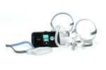 Black CPAP machine with display screen, hoses, and two face masks with head straps on a white background.