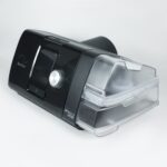A black ResMed AirSense 10 CPAP machine with a clear water chamber on a white background.