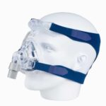A mannequin head wearing a clear CPAP mask with blue head straps for sleep apnea therapy.
