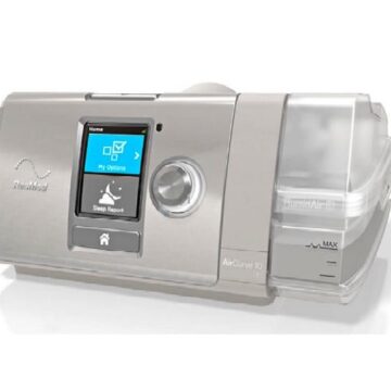 A ResMed AirCurve 10 CPAP machine with a digital display and attached humidifier.