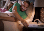 Man in bed wearing a CPAP mask, reaching to adjust a machine, with a woman lying beside him.