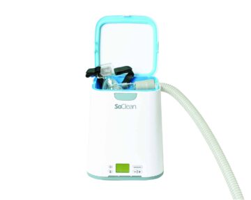 A SoClean CPAP cleaner with an open lid, mask, and attached hose visible on a white background.