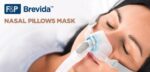 Woman sleeping while wearing a nasal pillows mask, with "F&P Brevida Nasal Pillows Mask" text on the image.