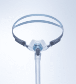 A CPAP nasal mask with headgear and hose against a plain light background, viewed from the front.