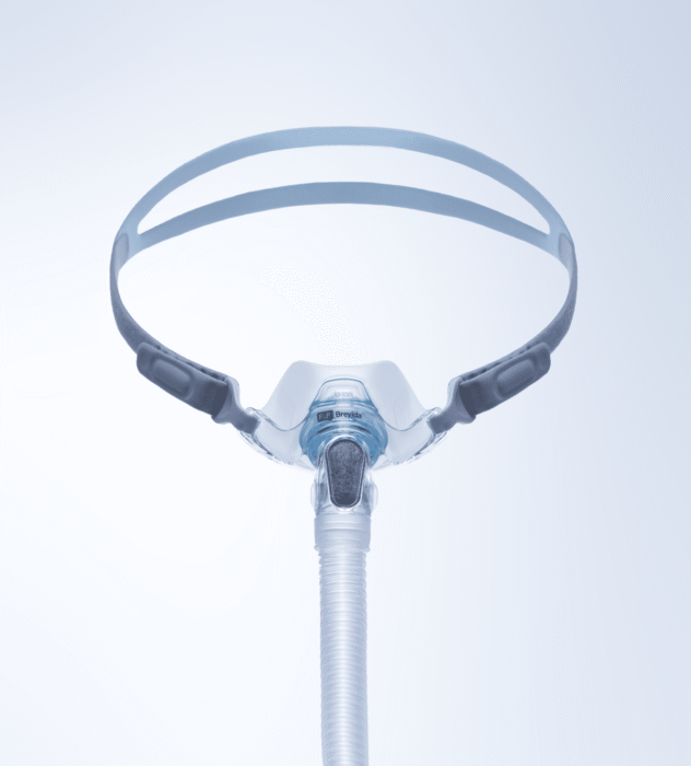 A CPAP nasal mask with headgear and hose against a plain light background, viewed from the front.