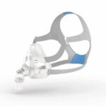 CPAP mask with gray straps and clear plastic face cover, used for sleep apnea therapy on a white background.