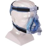 Clear mannequin head wearing a CPAP full face mask with blue and clear straps and headgear.