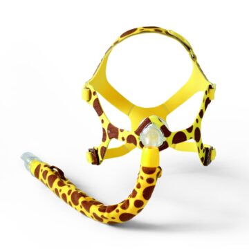 A CPAP mask with a yellow and brown giraffe print design on a white background.