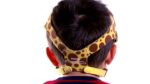 A child wearing a giraffe-print headgear from behind, the brand Philips Respironics visible.