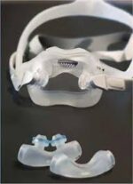 Clear nasal CPAP mask and two silicone nasal pillows on a dark background.