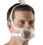 Man wearing a clear CPAP mask with headgear, viewed from the front against a white background.