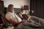 A man and woman wearing the ResMed AirFit F30 Full Face CPAP Mask in bed.