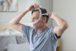 A man wearing a ResMed AirFit N30i Nasal CPAP Mask in bed.