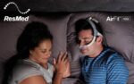 A couple sleeping in bed with the ResMed AirFit N30i Nasal CPAP Mask.