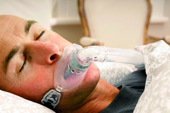 A man laying in bed wearing a Fisher & Paykel Oracle 452 Oral CPAP Mask (Fit Pack).
