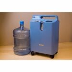 A Respironics Everflo Stationary Concentrator next to a bottle of water.