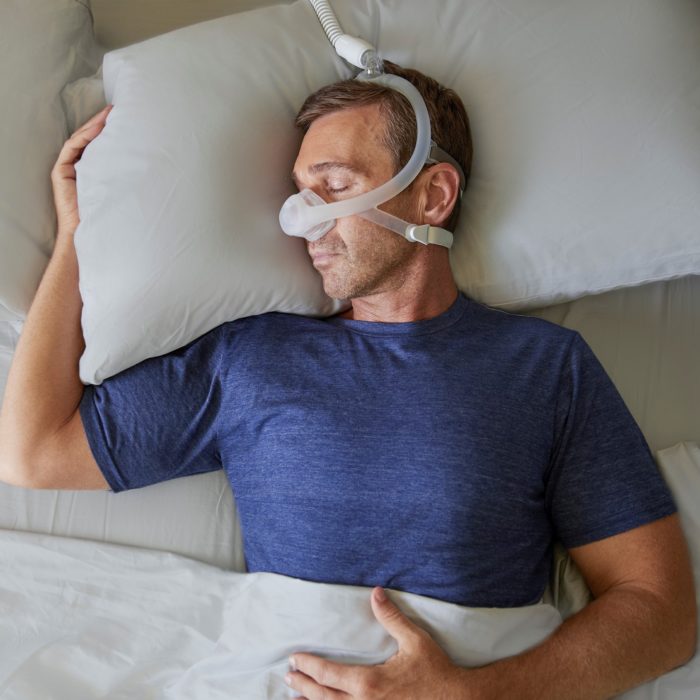 A man wearing a Respironics DreamWisp Nasal CPAP Mask (Fit Pack) while sleeping.