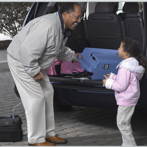 An older man and a little girl opening the trunk of an SUV to access Respironics Everflo Stationary Concentrators.