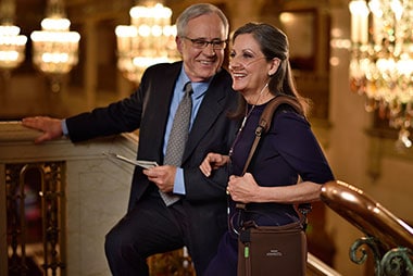 A man and woman in business attire standing on a Respironics Simply Go Mini Portable Oxygen Concentrator with Extended Life Battery.