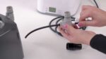 A person is using the So Clean Adapter for Fisher & Paykel Icon Series on a water dispenser.