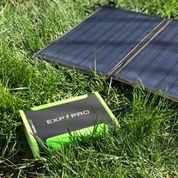 A green solar panel on the grass, equipped with the Expion48PRO Back Up Power Supply.