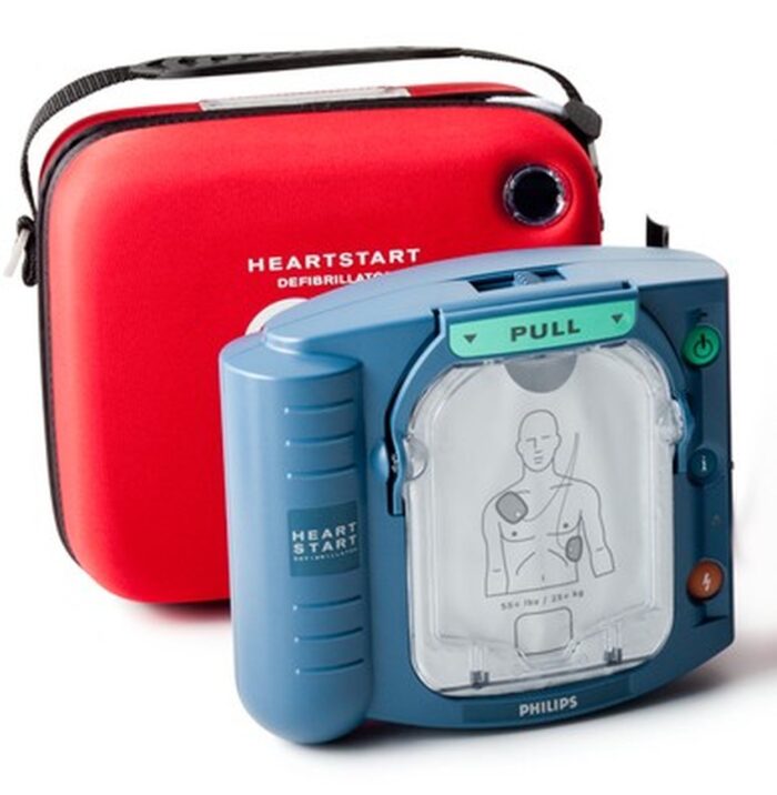 A Philips HeartStart OnSite AED defibrillator next to a red bag.