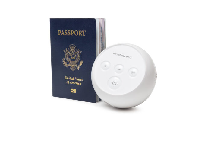 A US passport stands next to a round, white Transcend Micro Travel APAP Machine with buttons on a white background, perfect for those who wish to transcend traditional travel limitations.