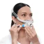 A person adjusting their ResMed AirFit F40 Full Face CPAP Mask, a top-quality product from ResMed, on their face.