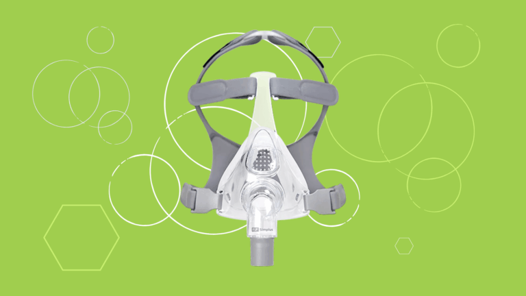 A Fisher & Paykel Simplus Full Face CPAP Mask with headgear displayed on a green background featuring white circles and hexagons.