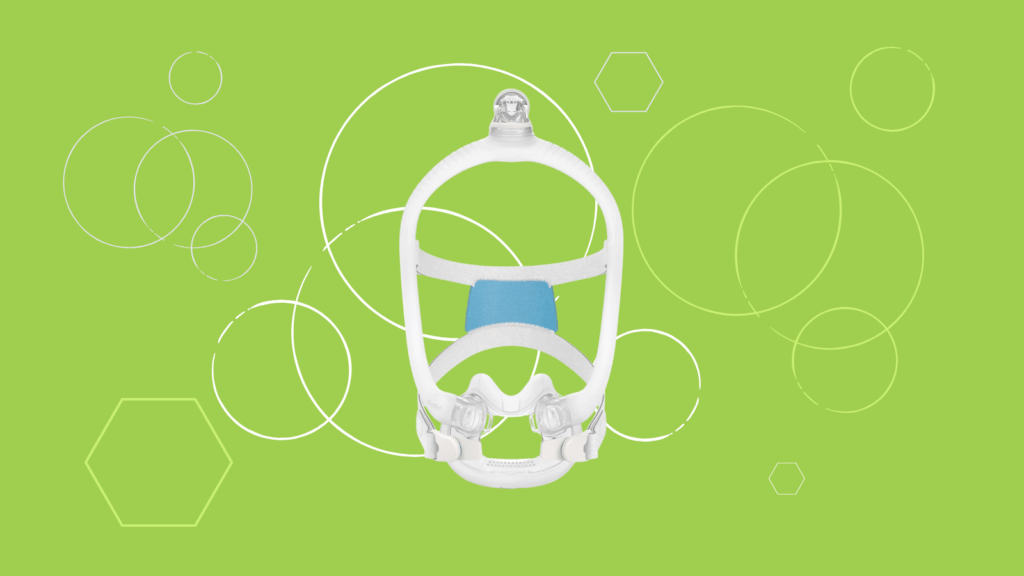 A white ResMed AirFit F30i full face CPAP mask with blue padding sits on a green background adorned with white geometric shapes.