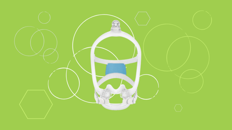 A white ResMed AirFit F30i full face CPAP mask with blue padding sits on a green background adorned with white geometric shapes.