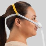 Woman in profile wearing the Fisher & Paykel Solo Nasal CPAP Mask (Fit Pack) with head straps for sleep apnea therapy, her hair pulled back in a ponytail.