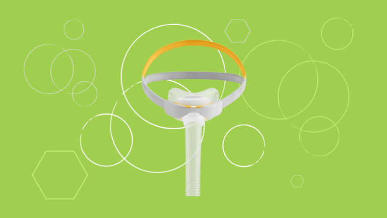 A Solo Nasal Mask by Fisher & Paykel with a strap and hose is displayed on a green background featuring white circles and hexagons.