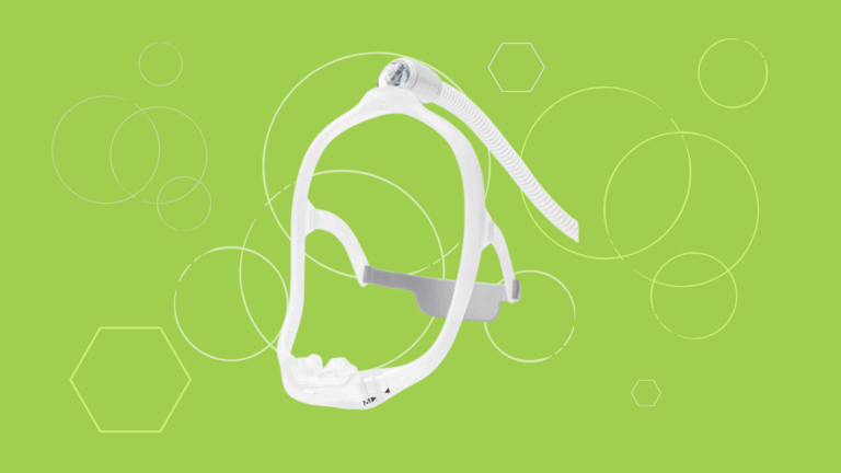 White Dreamwear Silicone Nasal Pillow CPAP mask with headgear and tubing on a green background featuring circular patterns.