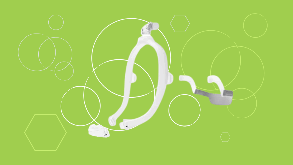 A white Respironics CPAP mask frame and headgear on a green background with circles and hexagons.