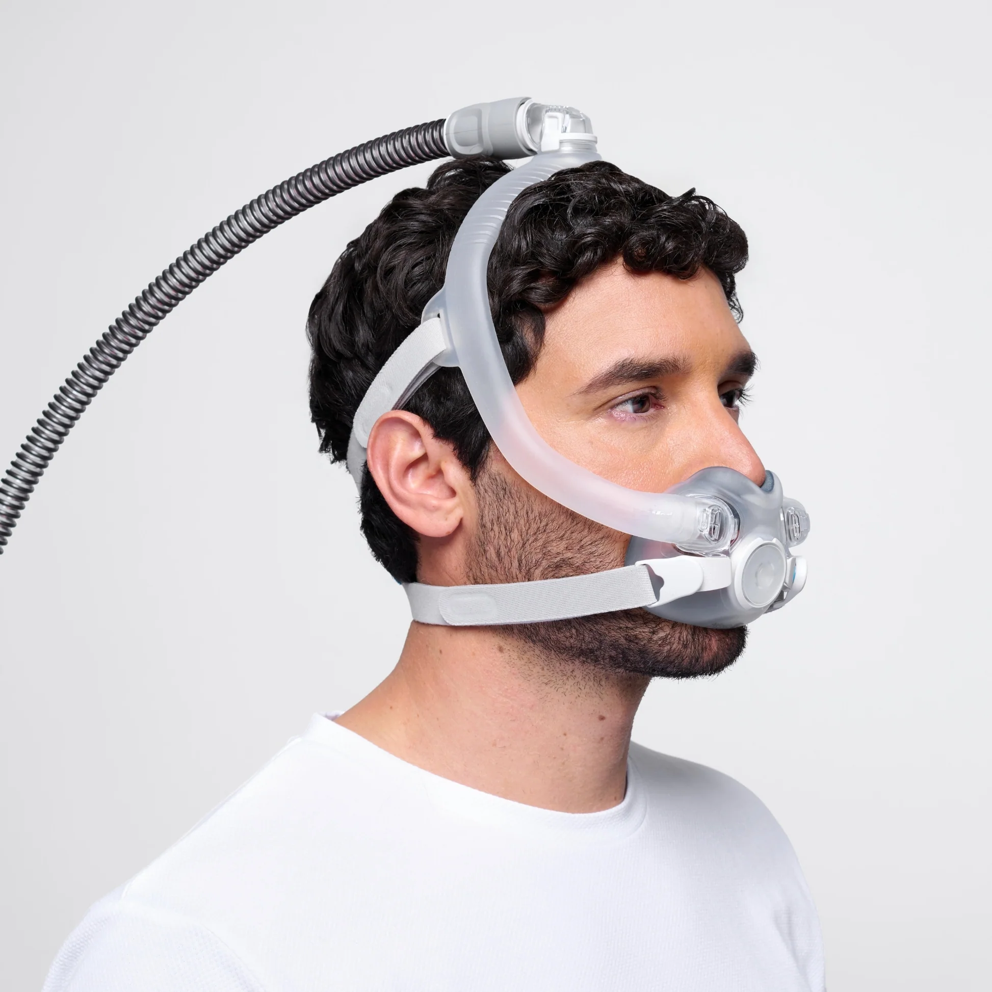A man wears a ResMed AirTouch F30i Comfort Full Face CPAP Mask, shown from the side against a plain background, emphasizing its comfortable and secure fit.